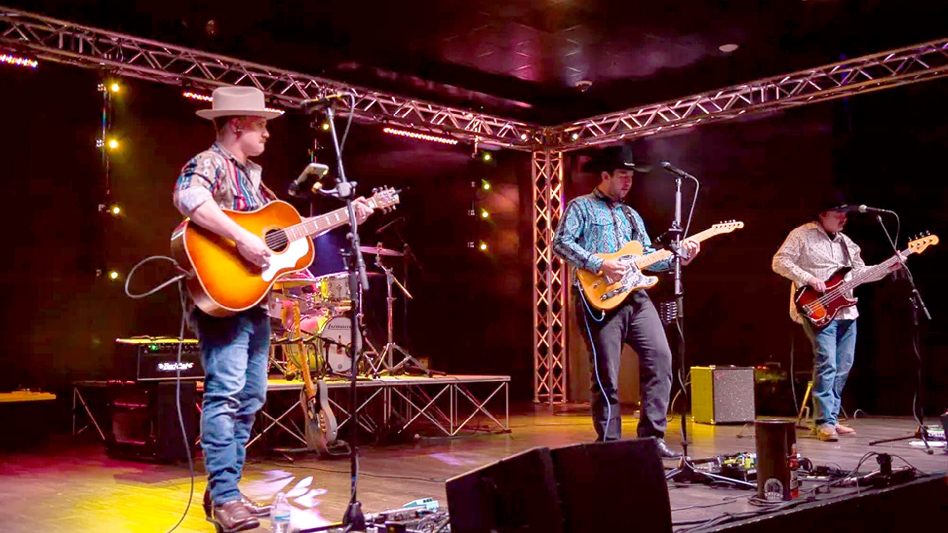 Whisky Outlaws band performing on stage with guitars and cowboy hats.